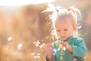 cute sweet little girl playing with flowers outdoors